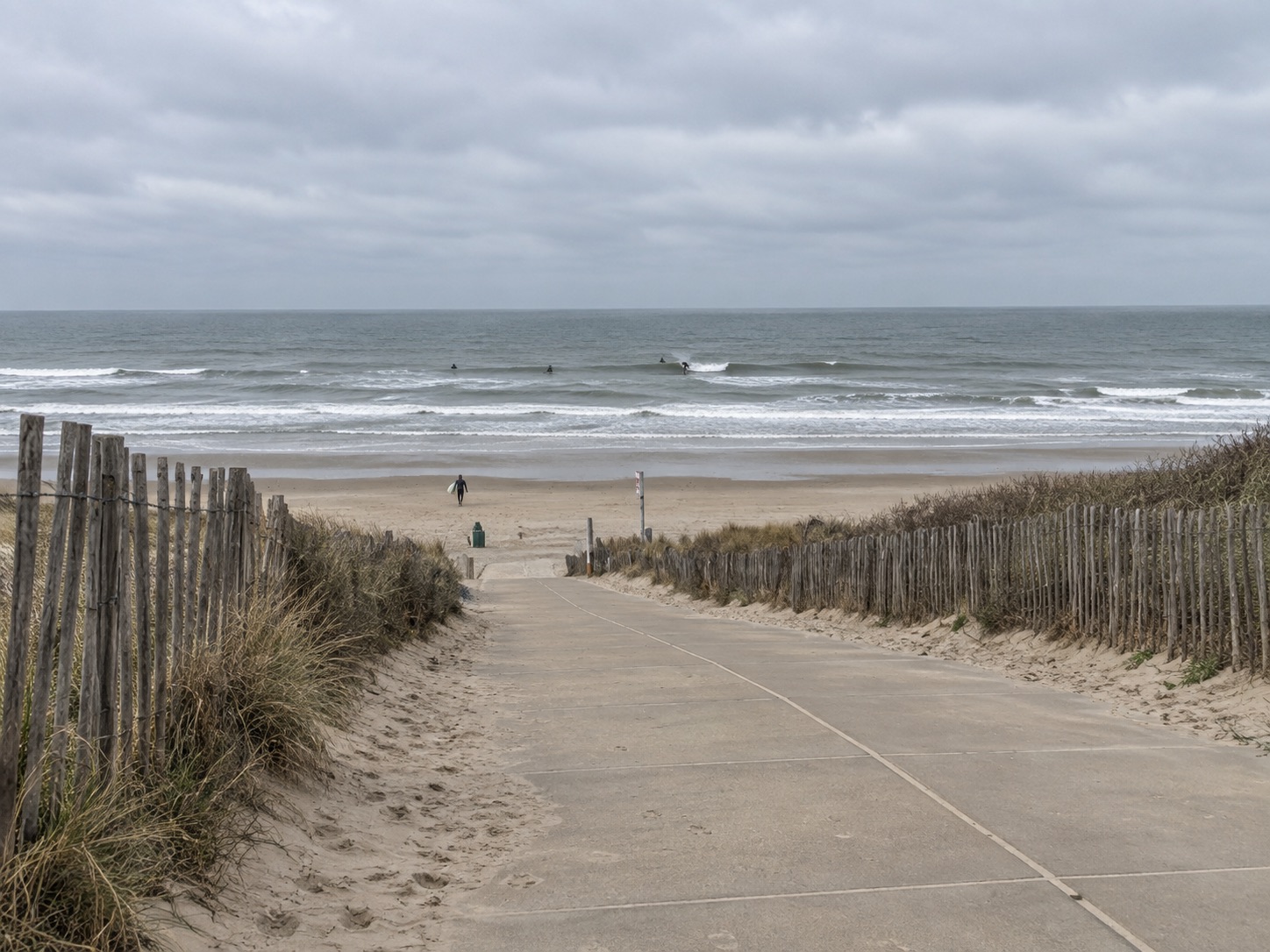 Strandopgang door de duinen met surfers in de branding bij Ter Heijde